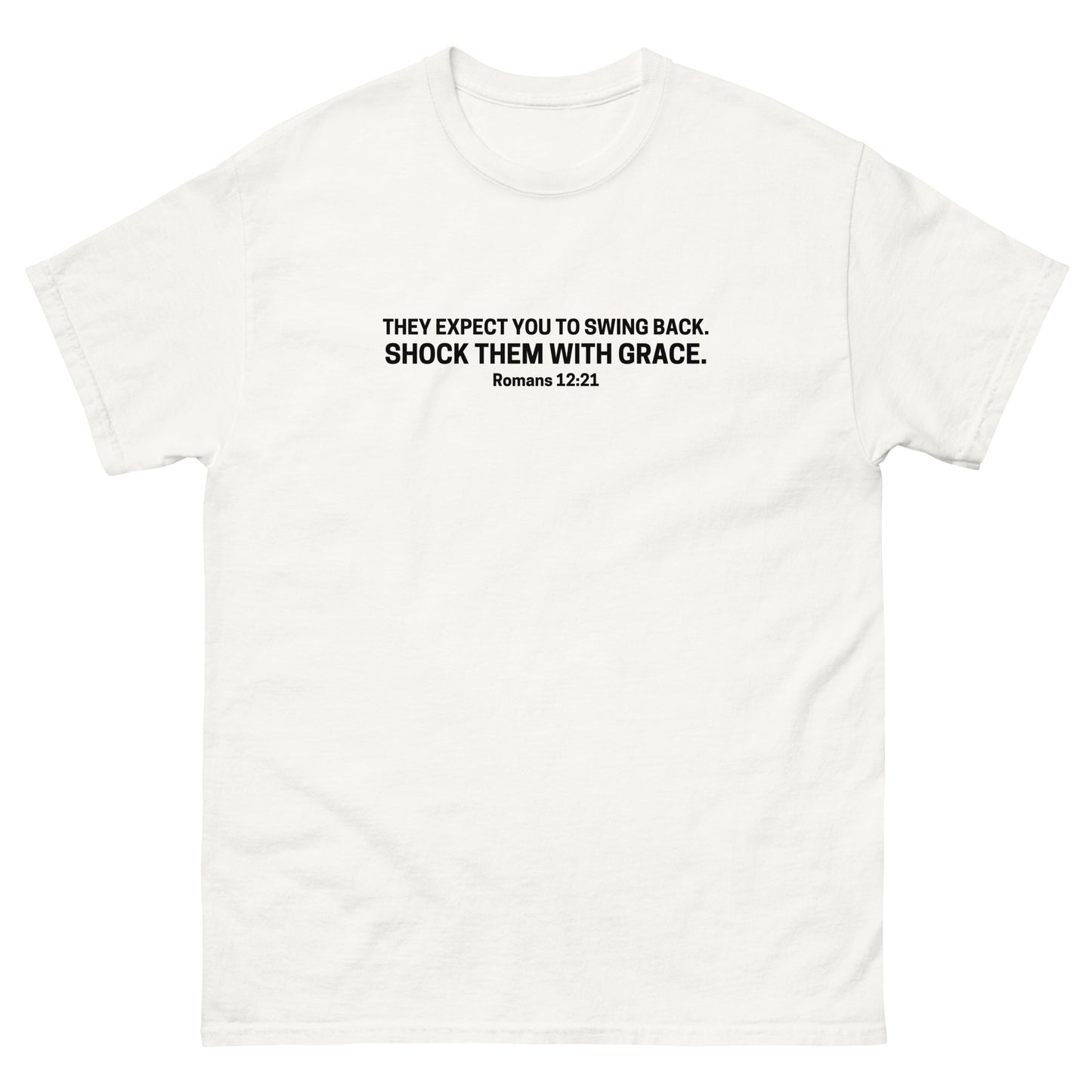t-shirt with black text on the front that reads 'They expect you to swing back. Shock them with grace. Romans 12:21,' displayed flat on a white background. white
